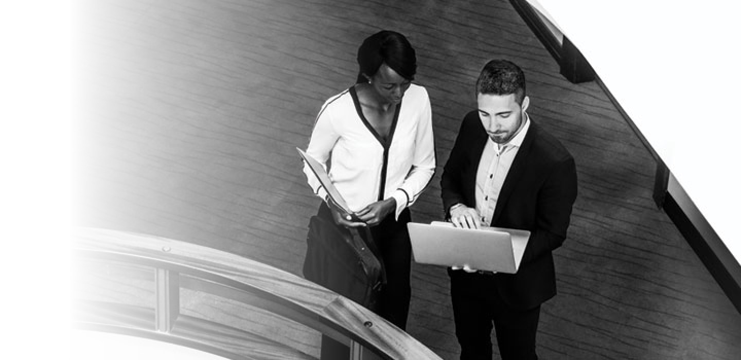A man and woman talking while looking at a laptop screen
