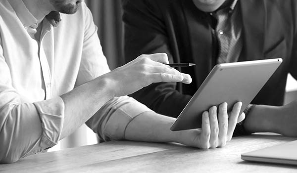 An advisor showing another advisor something on a tablet.