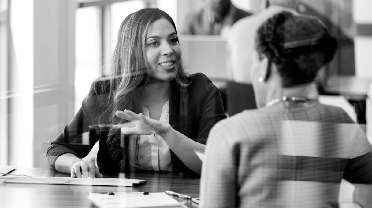 Two businesspeople sit at a table and have a discussion.