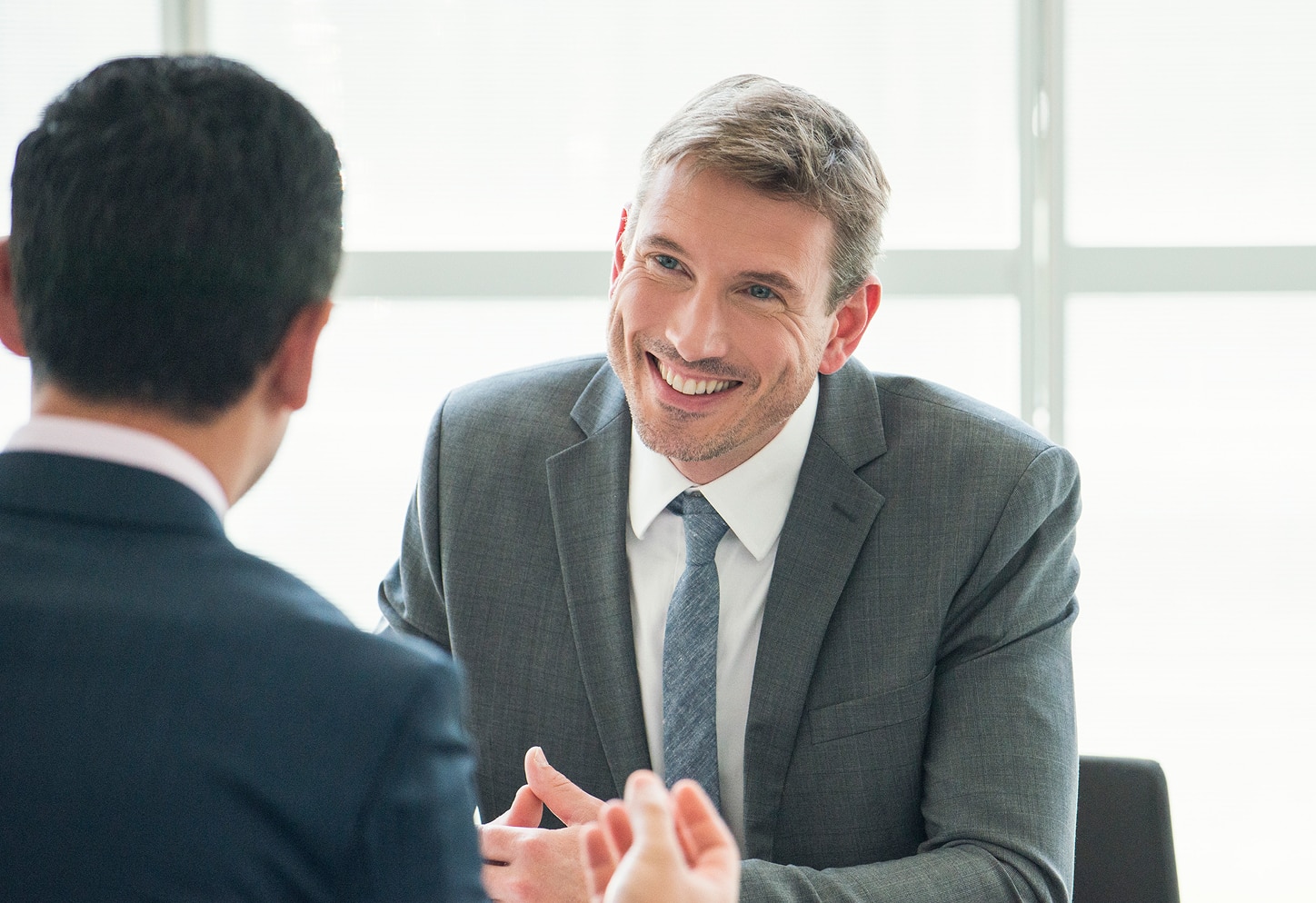 A smiling advisor in a suit looks directly at a client.