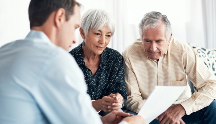 A businessperson reviews a document with two other people. 