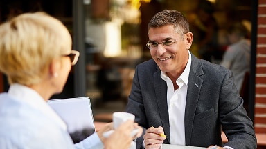 A smiling man gets coffee with a business associate.