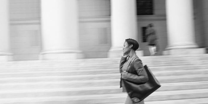 Woman advisor walking and talking on a cell phone with a fast-moving background.