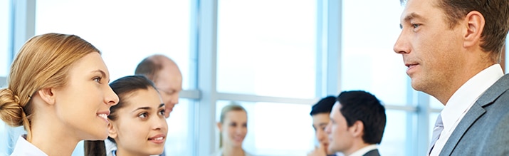 Five professionals in business attire are having a friendly discussion with an older peer.