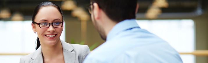 A woman in glasses interviews a young intern.